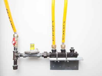 A simple house natural gas pressure regulator and manifold mounted to a wall. The main line coming into the house is on the left and the manifold distributes gas to a fireplace and furnace.